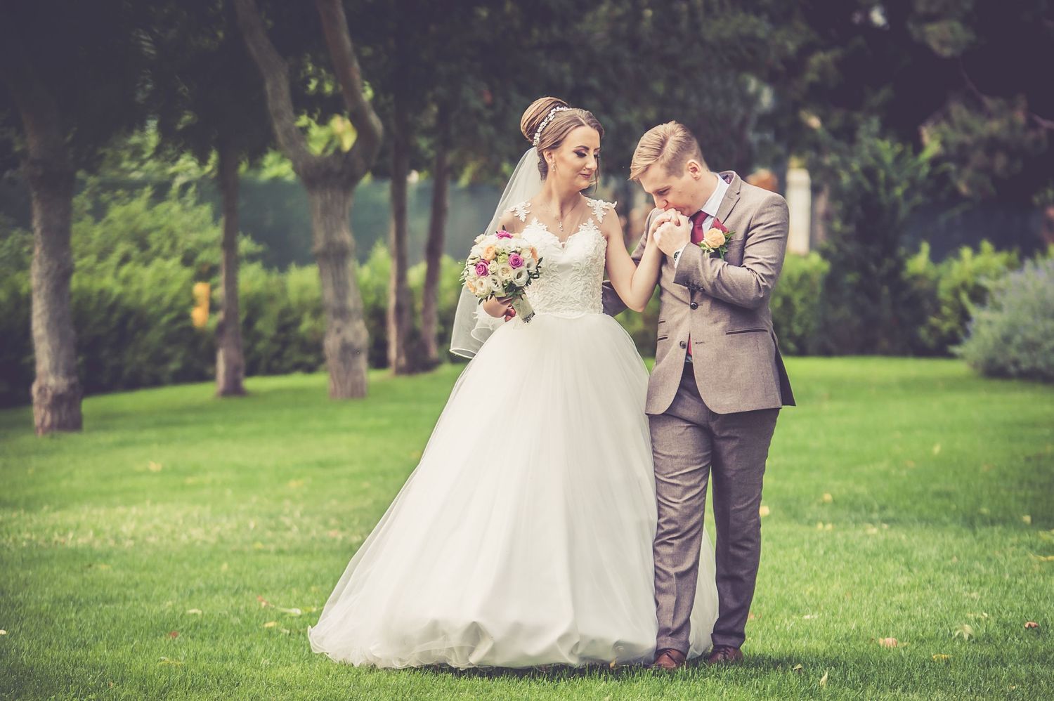 Wedding couple walking together on green lawn with soft vintage filter effect.