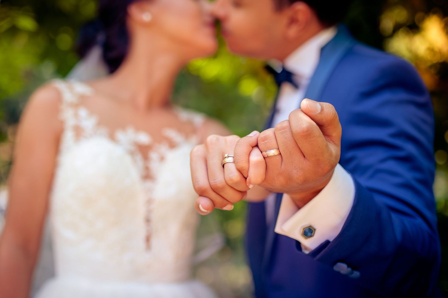 Close up of newlyweds holding hands showing wedding rings.