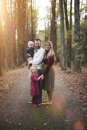 Family enjoying an autumn walk together on a tree-lined trail with golden sunlight filtering through the leaves.