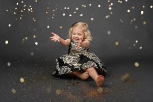 A playful photoshoot against a dark background with glittering bokeh effects.