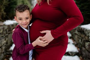 A family poses together in burgundy outfits against a winter landscape.