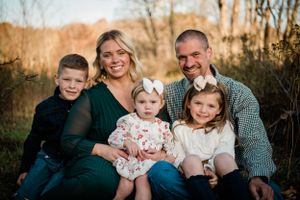 A family sits together outdoors for a casual portrait session during autumn.
