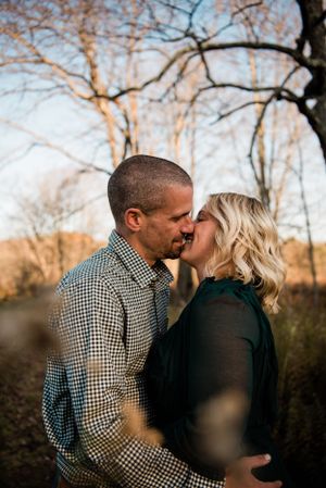 A romantic couple shares an intimate moment in front of autumn trees.