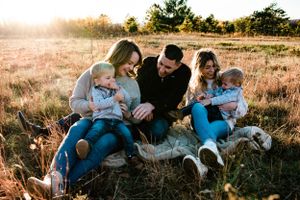 Tender family moment captured during golden hour in a rustic outdoor setting with glowing sunlight.