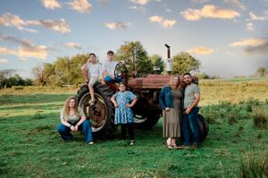 A group poses beside a vintage red tractor during golden hour.