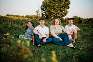 Four people sit casually together in a sunlit garden setting.