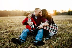 Family relaxing together on grass during golden hour sunset.