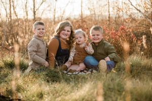 Family group photo session in autumn field with tall grass.