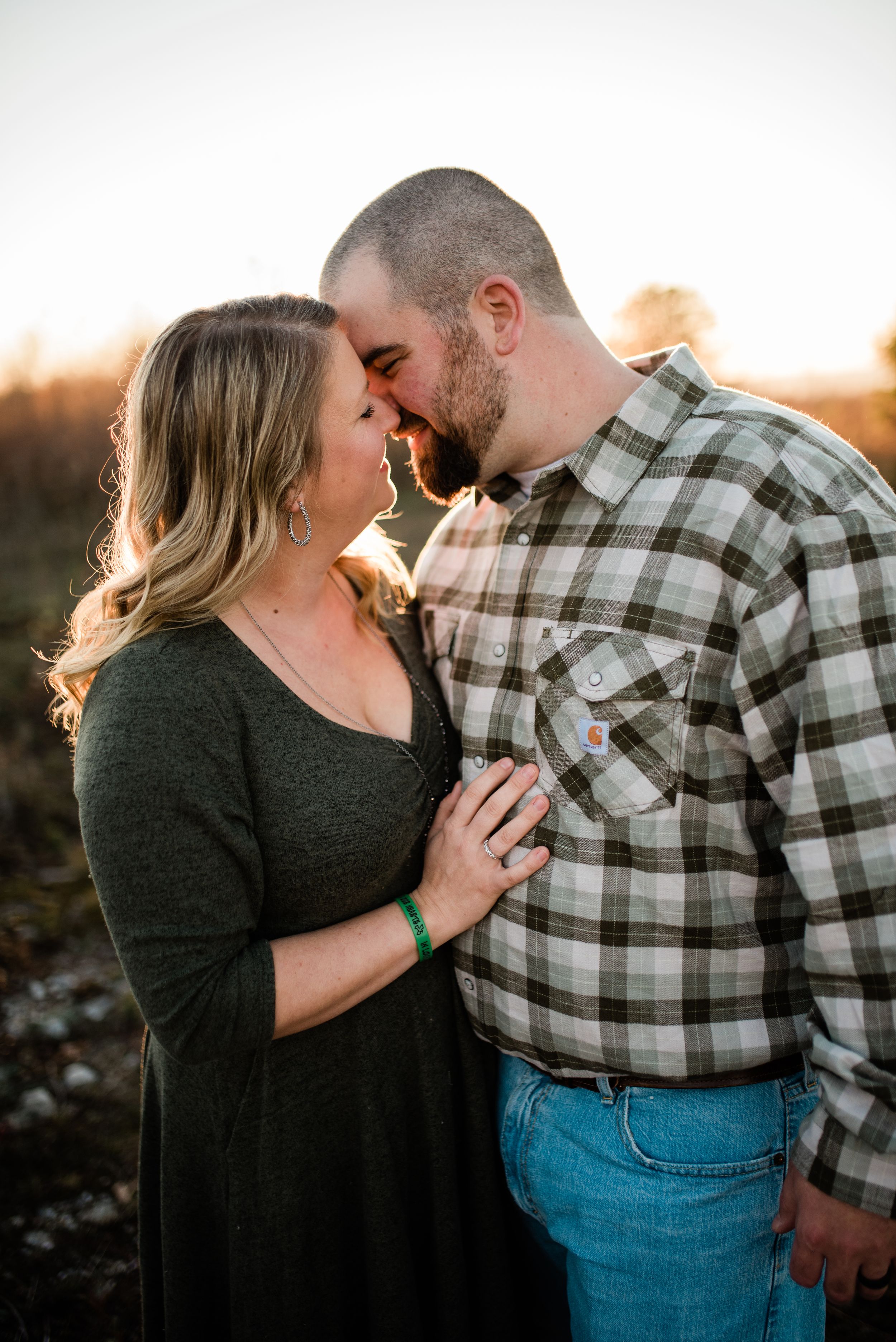Couple sharing intimate moments at sunset wearing casual attire.