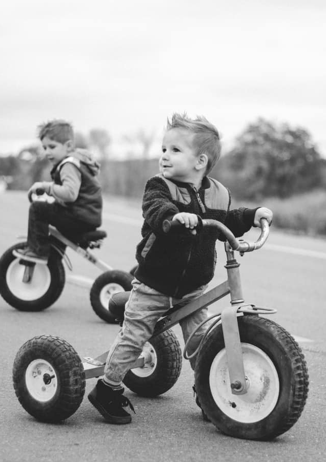 Series of black and white photos showing young child playing with large wheeled toy.