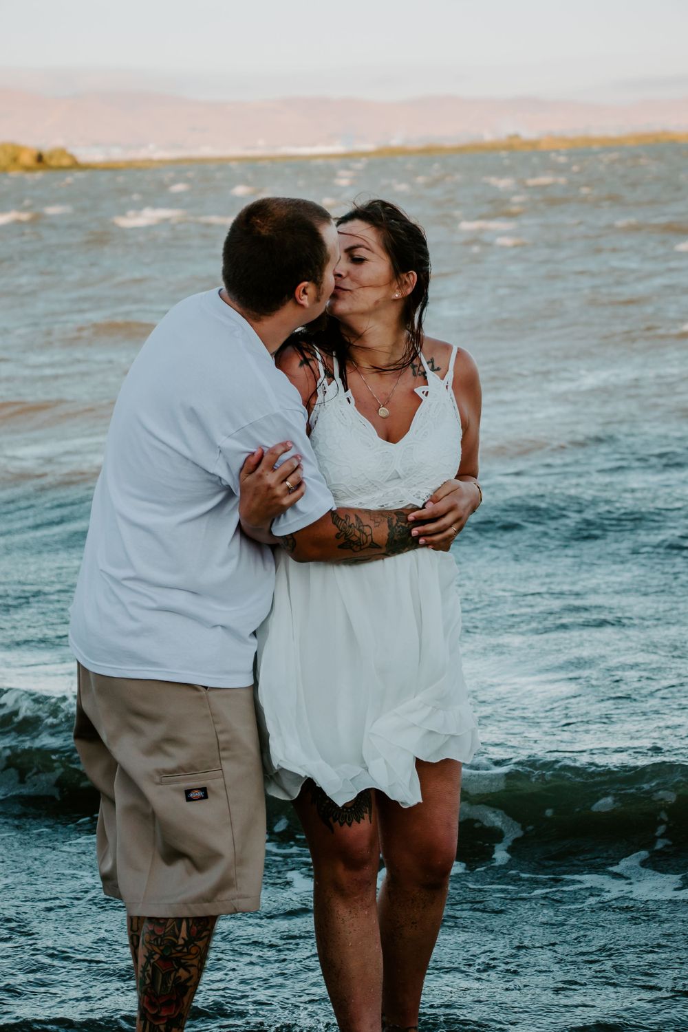 A romantic moment captured between a couple by the ocean at sunset.
