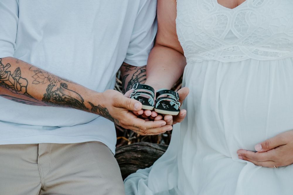 Close-up of hands holding sandals against white dress and casual attire.