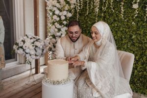 A couple cutting their elegant white wedding cake together.