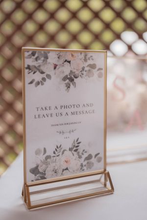 Elegant framed wedding sign with floral design asking guests to take photos and leave messages.