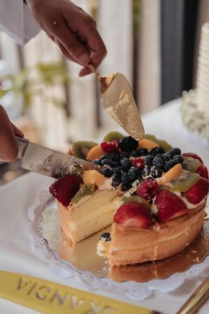 A beautiful fruit-topped cheesecake being served with fresh berries and decorative garnishes.