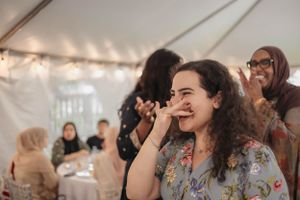 Wedding guests laugh and celebrate during a joyful moment at an indoor reception.