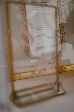 Close-up of a wedding document with signatures in a gold frame.