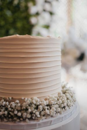 Simple blush pink wedding cake with textured horizontal lines and baby's breath flowers at the base.
