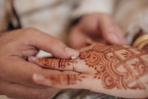 Close-up shot of intricate henna design being applied to someone's hand.