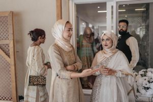 Wedding guests in traditional attire gather indoors during a celebration.