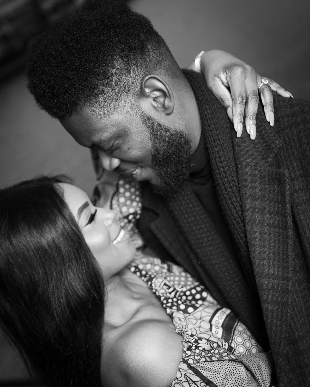 Black and white romantic couple portrait with man leaning in close to smiling woman.