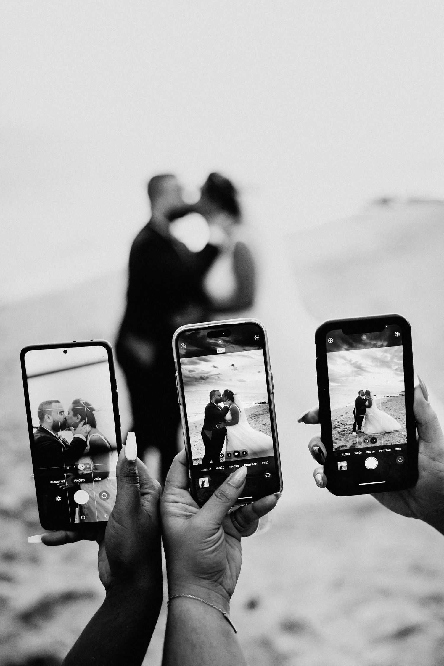 Series of hands holding phones capturing a romantic photoshoot silhouetted against a bright background.