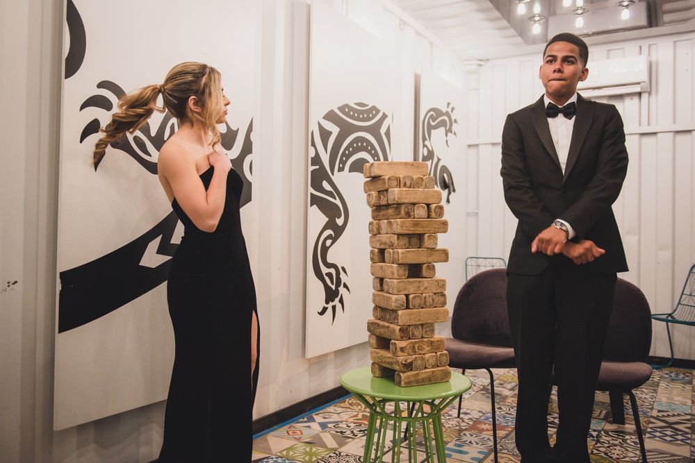 Two people playing Jenga game at formal event with artistic wall decorations.