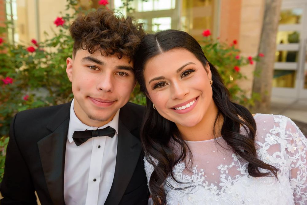 Close-up formal portrait of couple in wedding attire with red roses in background.