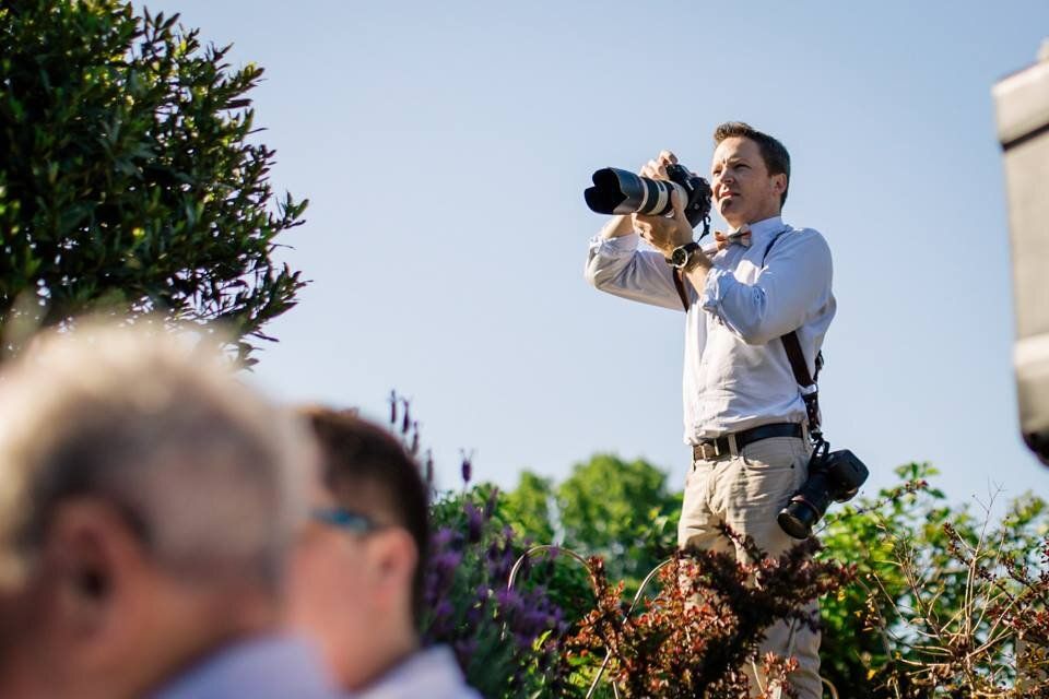 A photographer captures shots with a telephoto lens outdoors at a sunny event.