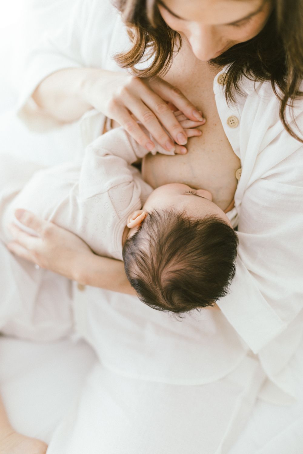 Close-up view of nursing baby in peaceful indoor setting with white tones.