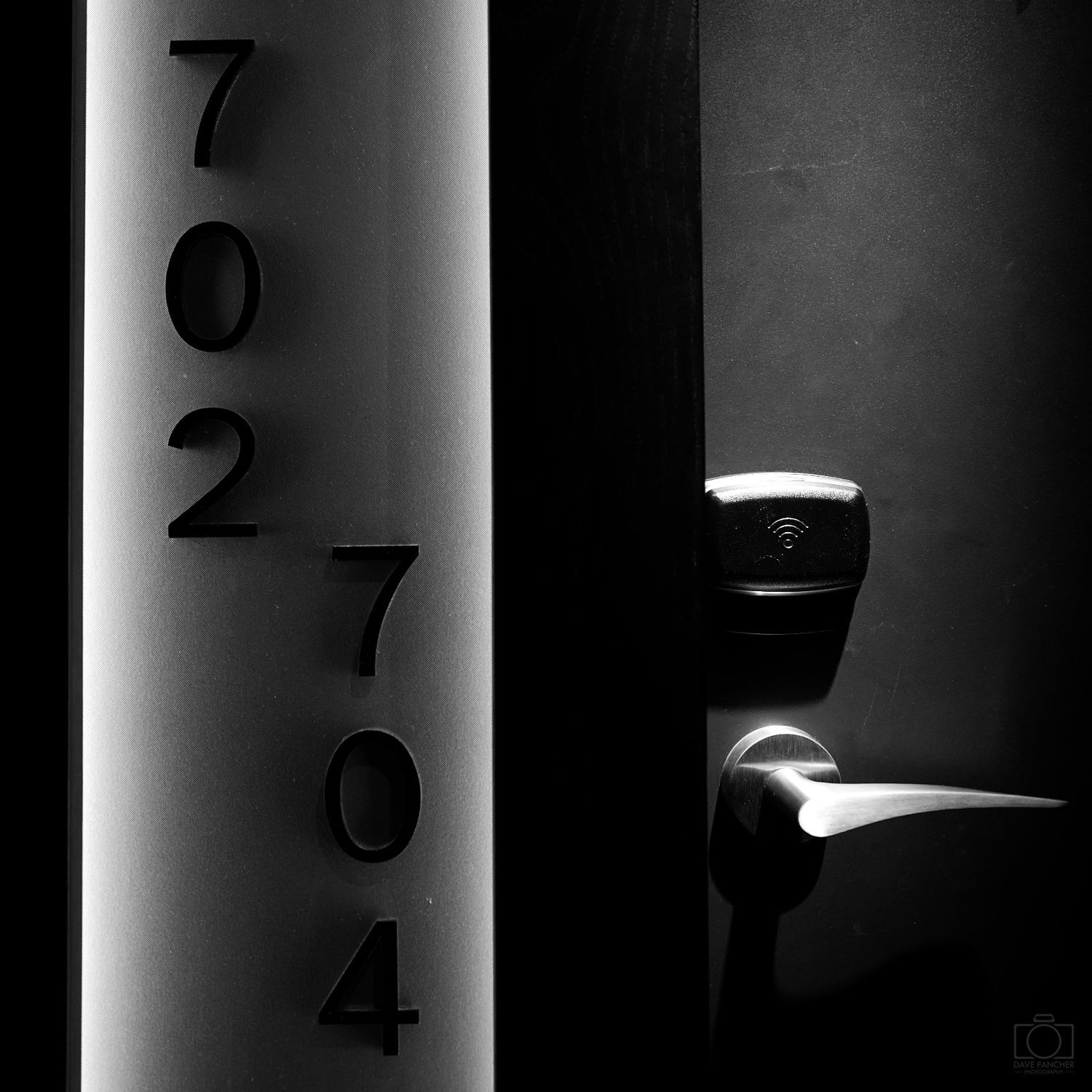 Black and white image of the hotel room door handle and numbers