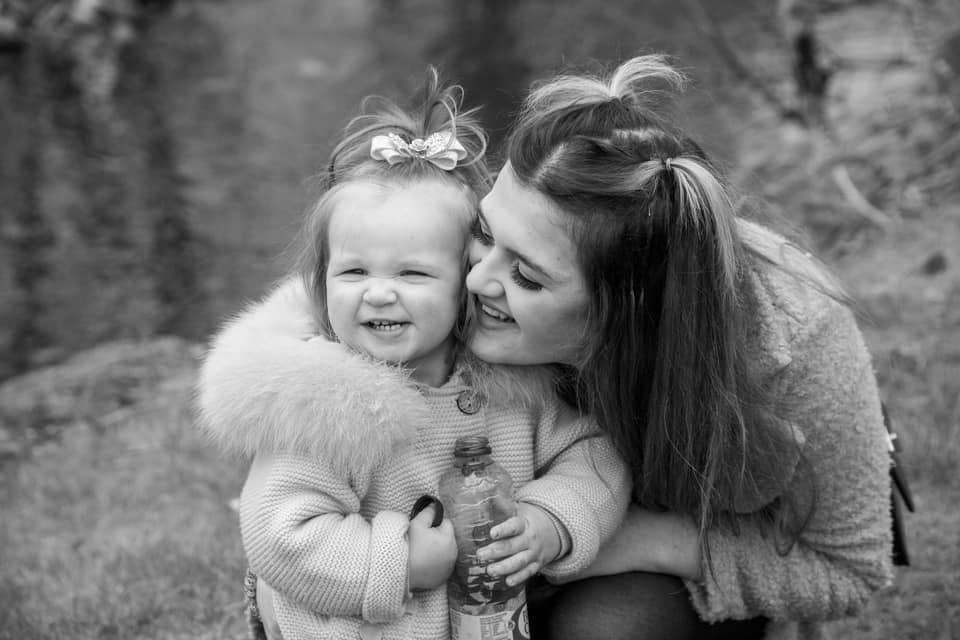 A tender black and white portrait of a heartwarming embrace between parent and child outdoors.