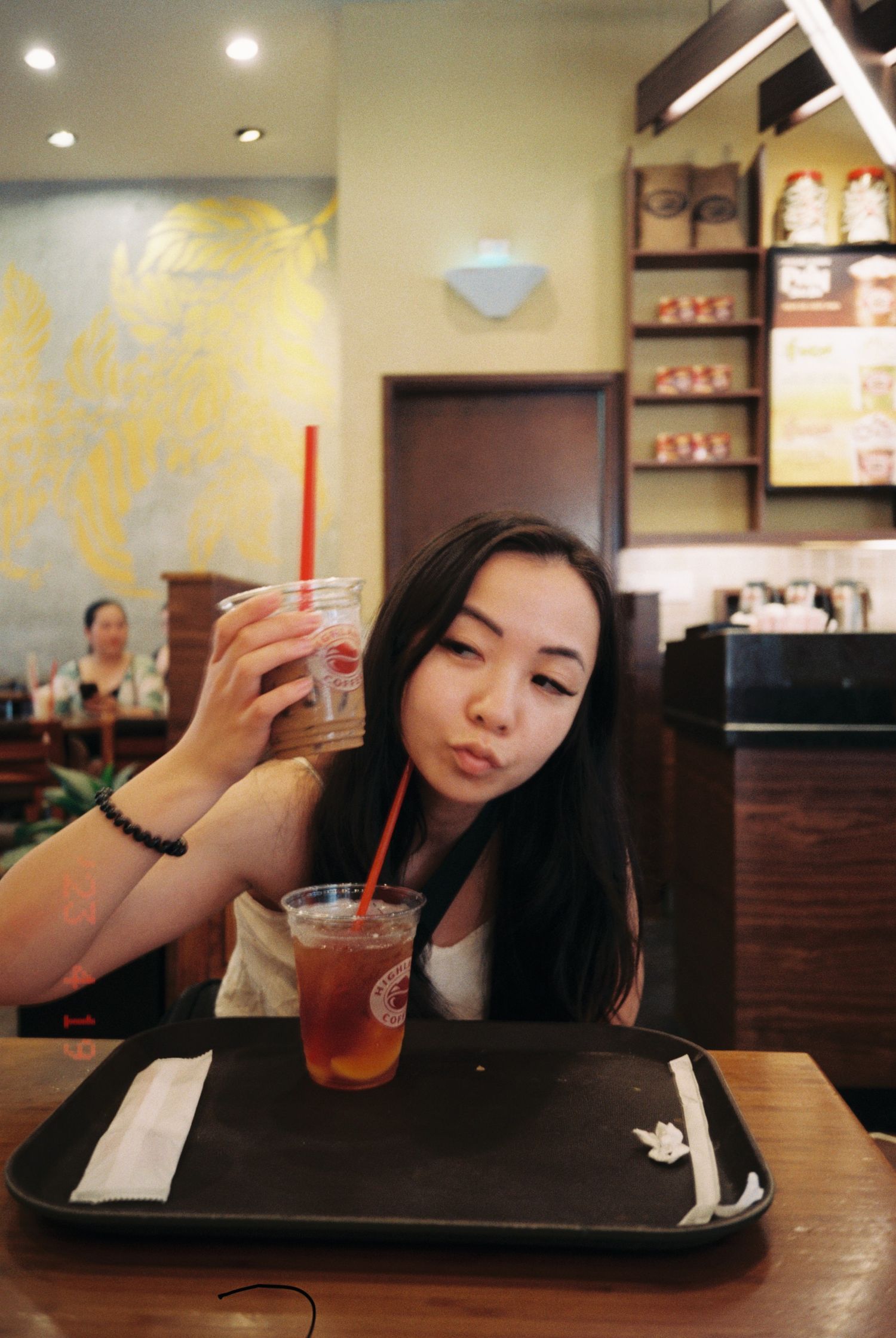 Person enjoying beverages at a casual restaurant counter with warm lighting and dark wood decor.