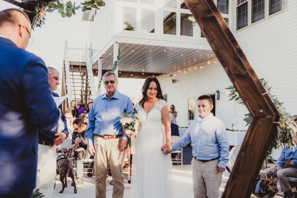 Wedding ceremony setup with wooden arch and floral decorations in an indoor venue.