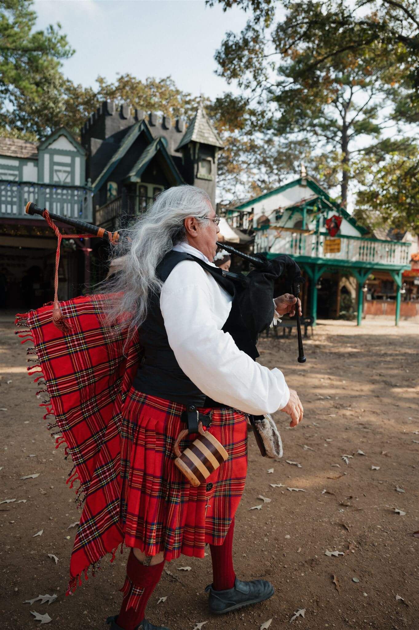 Bagpiper in traditional Scottish attire performs at a Renaissance festival.