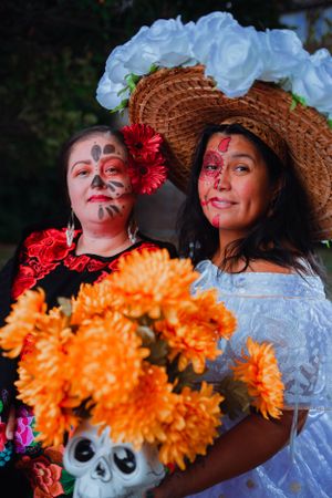 Day of the Dead celebration featuring traditional face paint and a decorative straw hat with vibrant orange marigold flowers.