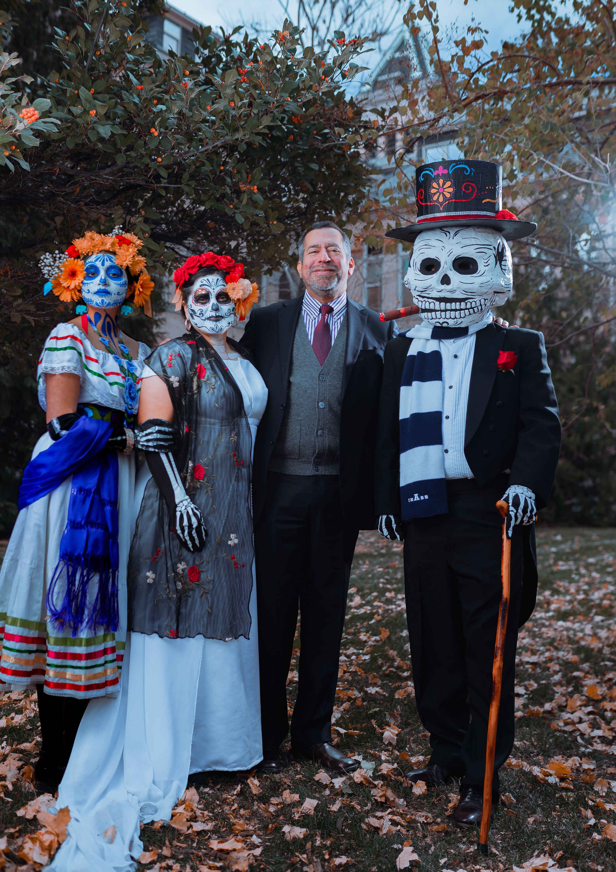 Group photo of Day of the Dead celebrants in traditional skeleton costumes and formal attire.