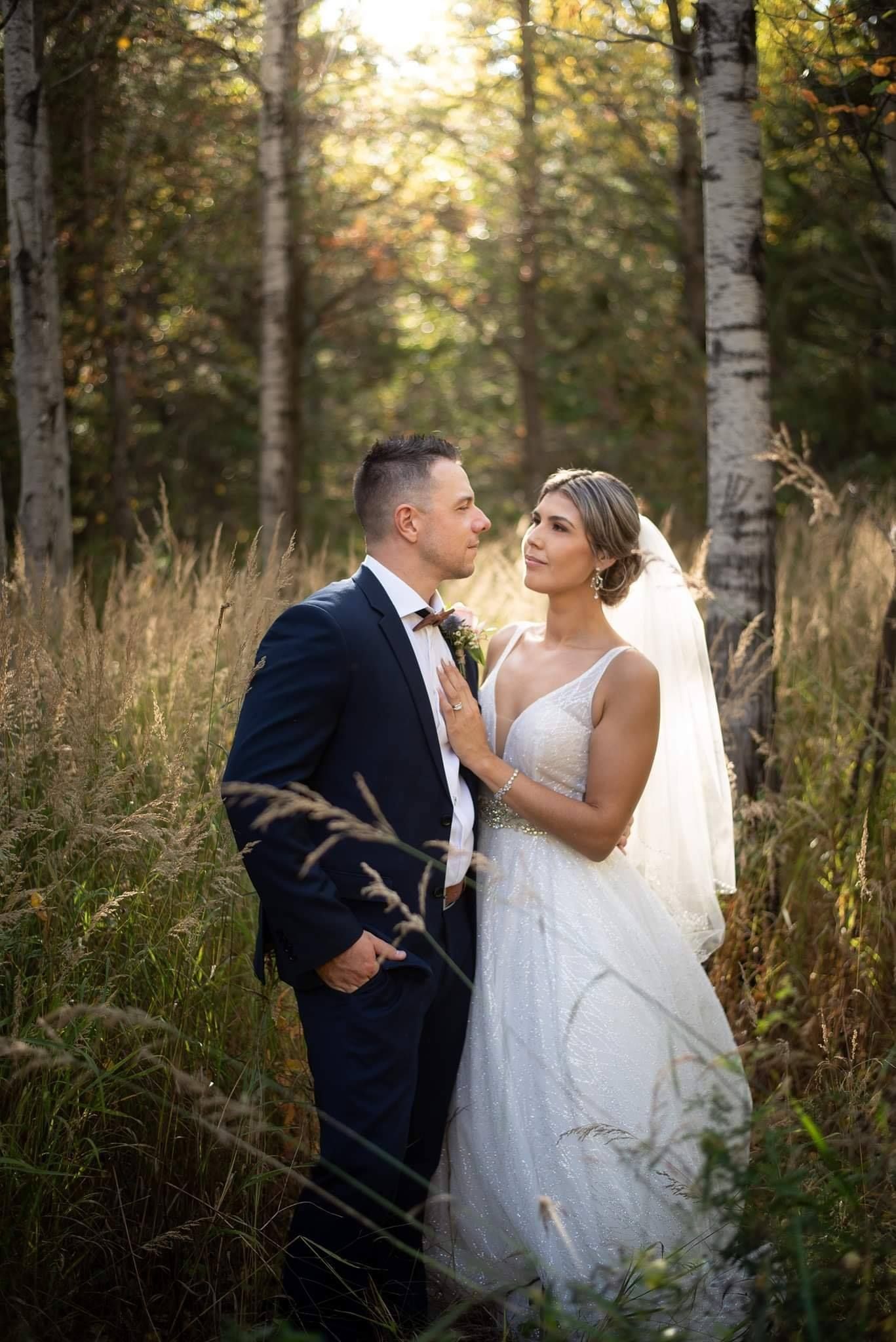 Wedding couple poses intimately among birch trees during golden hour.