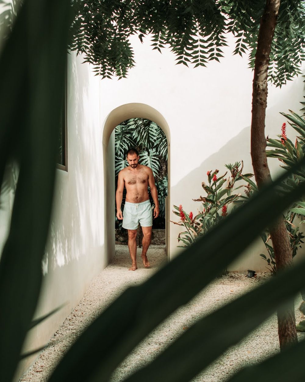 travel photography man in arched doorway in tulum mexico plants and palm trees