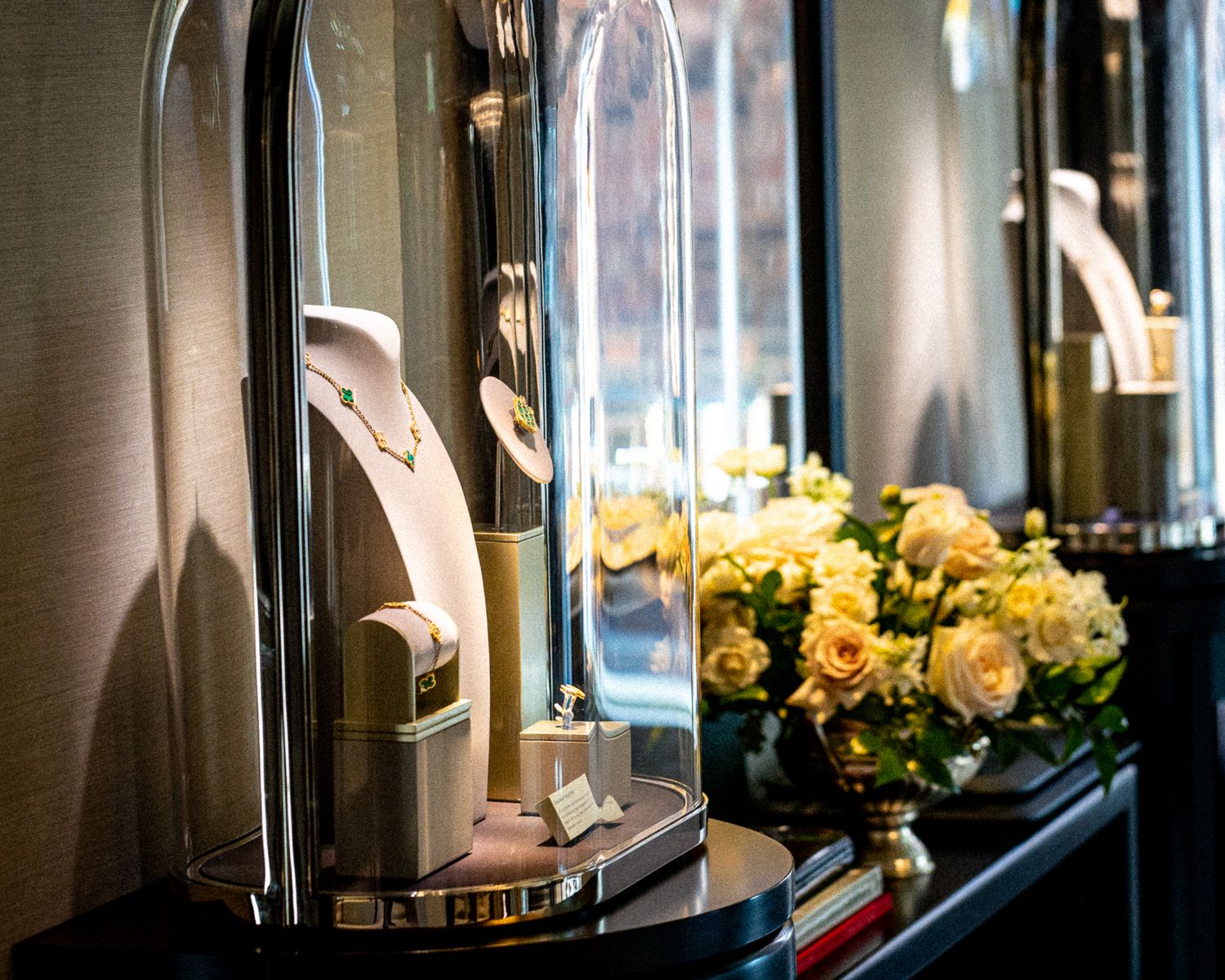 Luxury jewelry display case with yellow roses and glass dome showcases in an elegant retail setting.