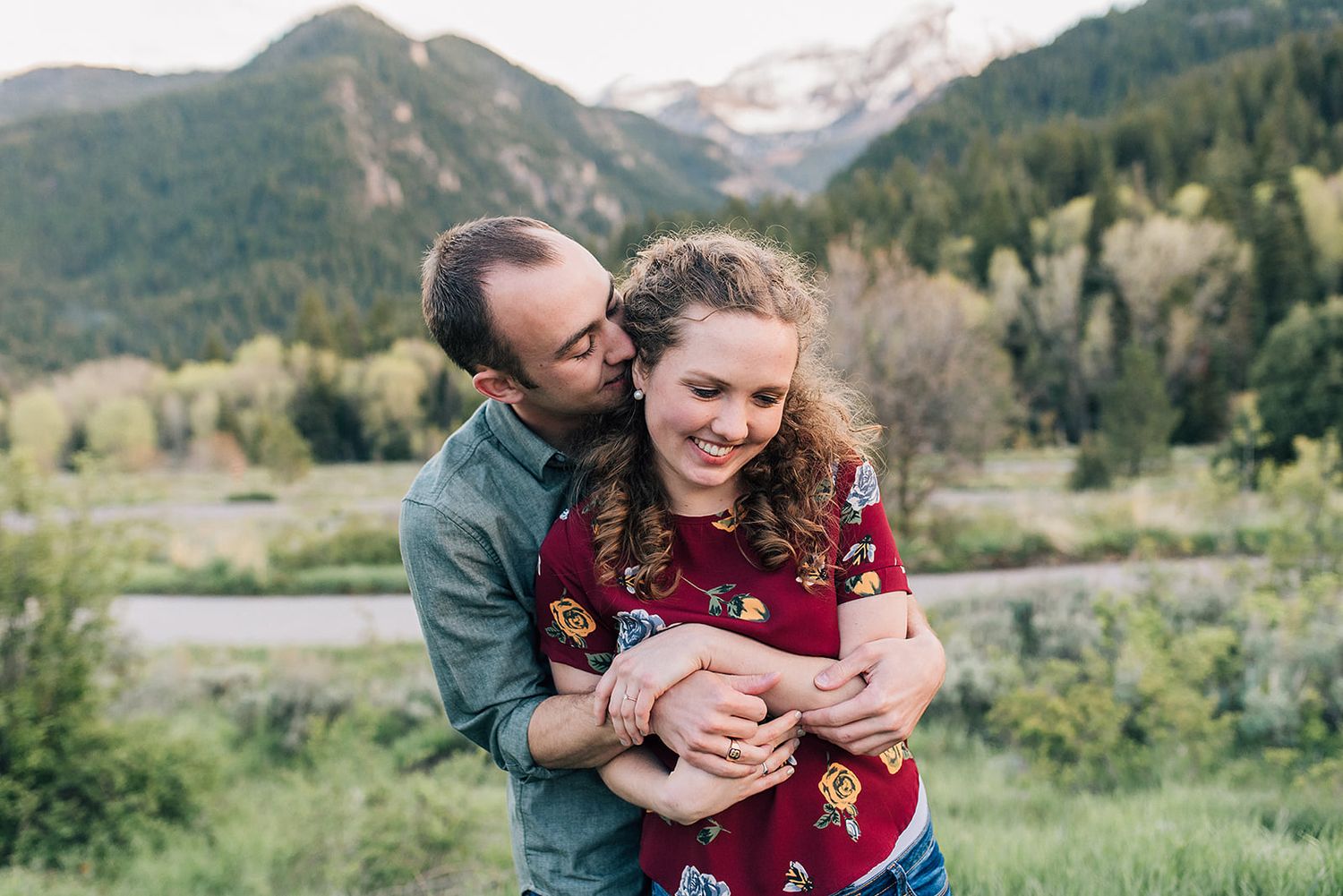 A couple shares an intimate embrace against a backdrop of mountain peaks and autumn foliage.