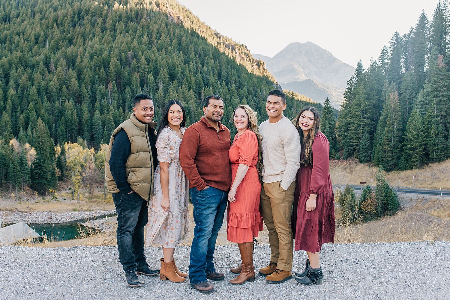A group poses together on a mountain viewpoint with evergreen forests and peaks in the background.
