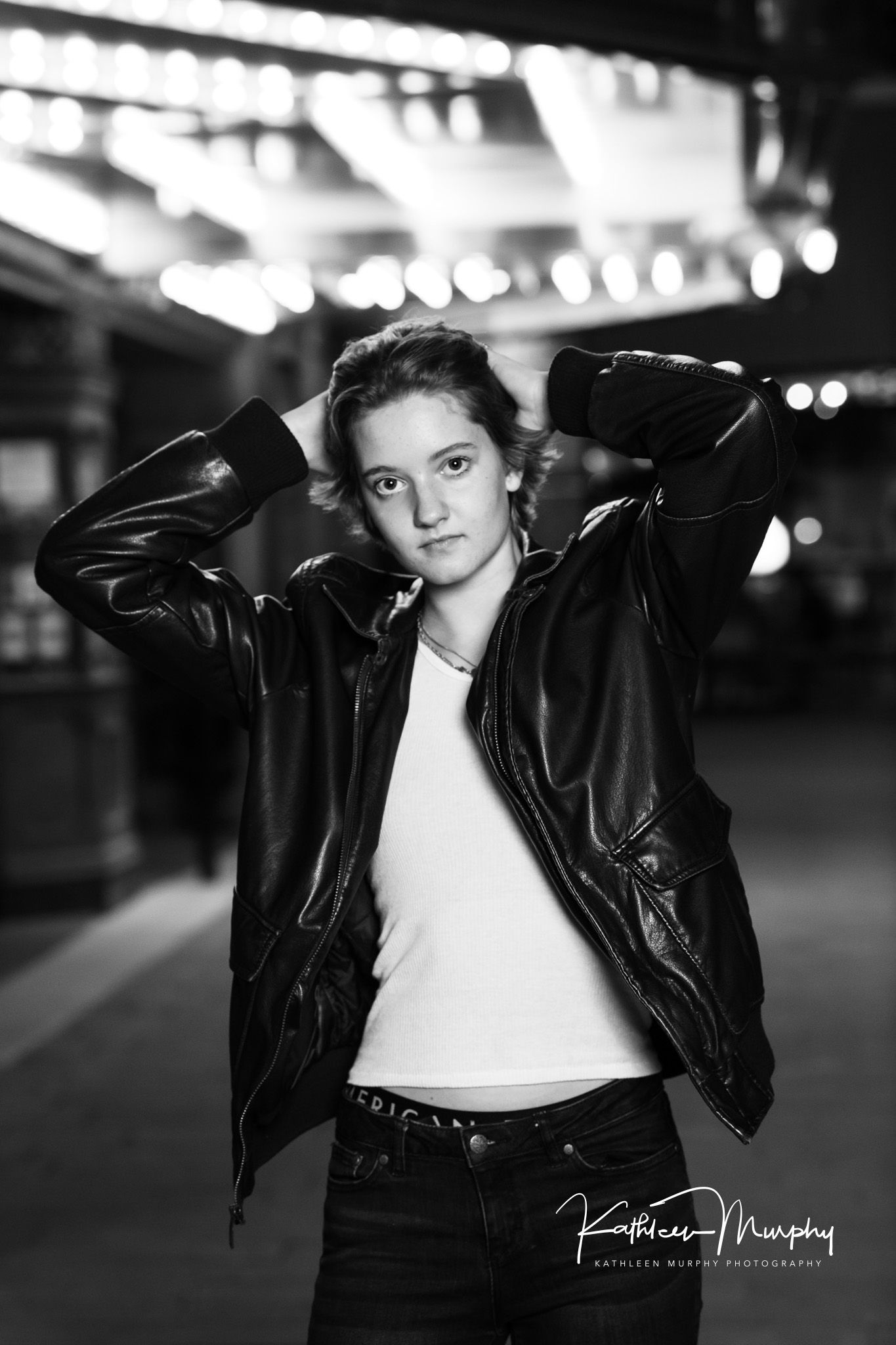 Dramatic black and white portrait in leather jacket against bokeh lights background.