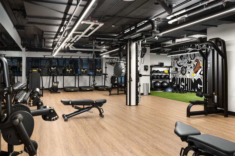 Spacious fitness center with weight machines, bench press stations, and industrial ceiling design.