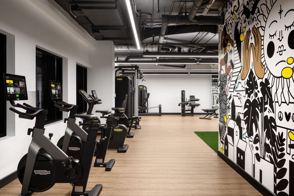Indoor cycling area with row of stationary bikes and black and white graphic wall mural.