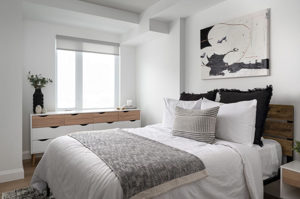 Modern bedroom with black and white artwork, built-in window bench, and plush bedding.