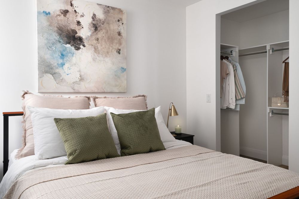 Elegant bedroom featuring abstract artwork, olive green pillows, and built-in closet space.