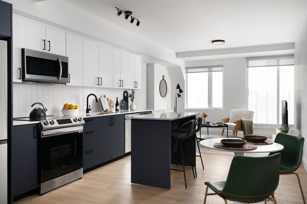 Modern black and white kitchen with green accent chair in open concept office space.