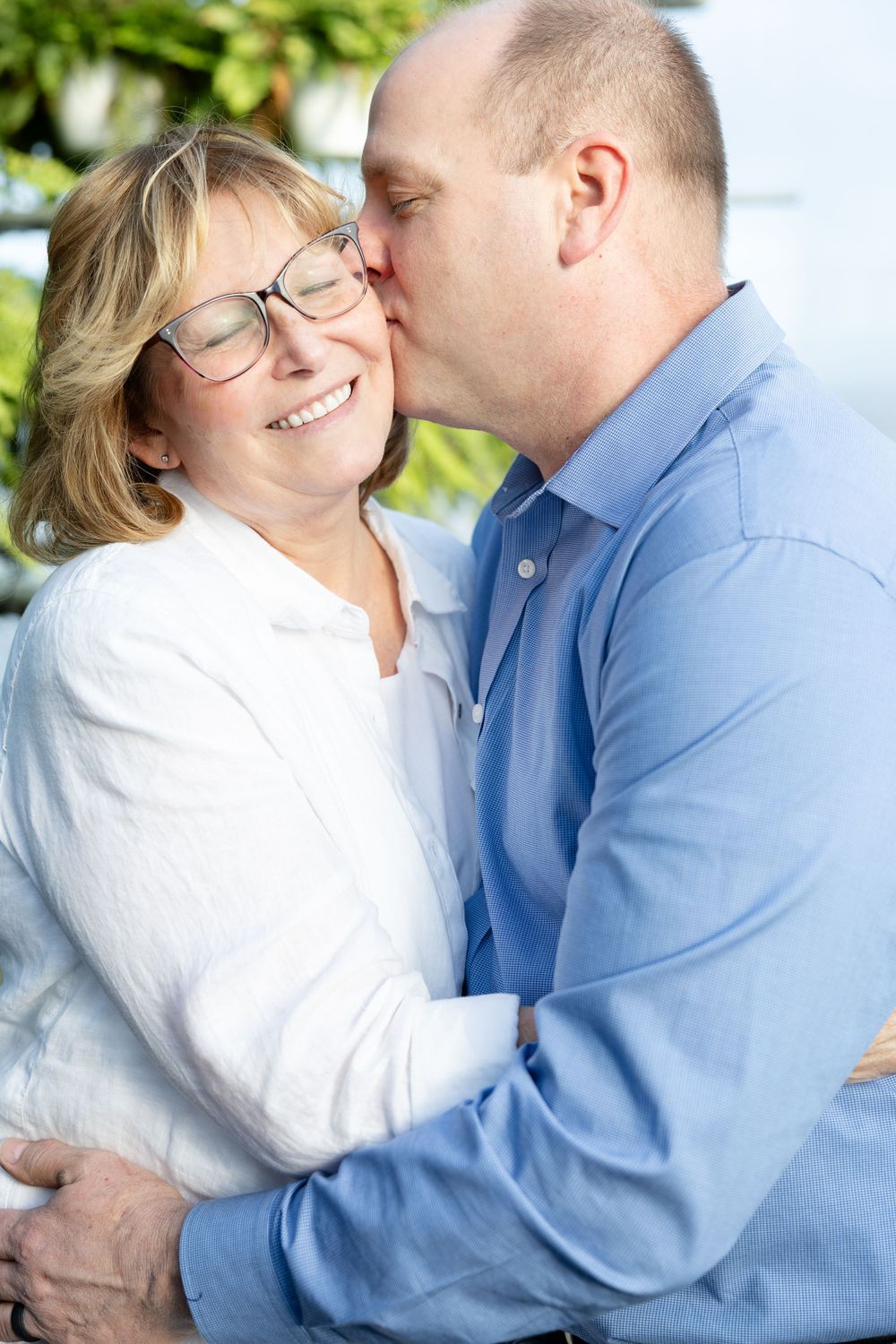 Husband Kissing Wife with Greenery in Background