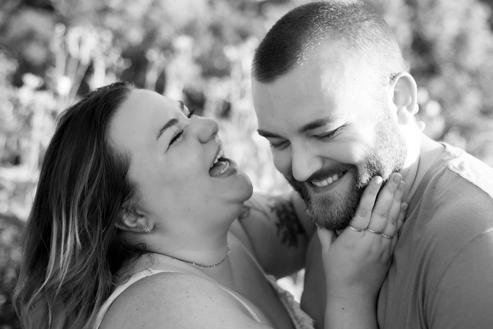 Engagement couple snuggling with her hand on his jaw.